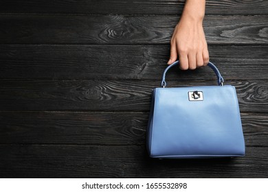 Woman Holding Small Bag On Black Wooden Background, Top View. Space For Text