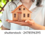 A woman is holding a small house in her hands. house selling and renting a house. own a house