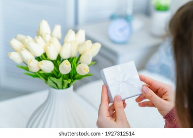 Woman Holding Small White Gift Box With Jewelry And Bouquet Of White Tulips Flowers On Woman Day. Concept 