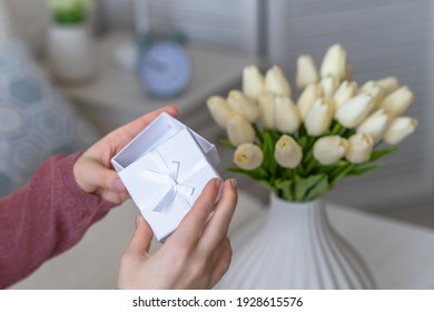 Woman Holding Small White Gift Box With Jewelry And Bouquet Of White Tulips Flowers On Woman Day. Concept