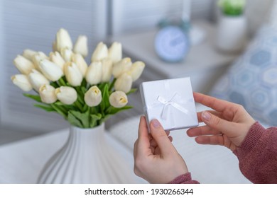 Woman Holding Small White Gift Box With Jewelry And Bouquet Of White Tulips Flowers On Birthday. Concept