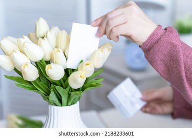 Woman Holding Small White Gift Box And Greeting Card With Bouquet Of White Tulips Flowers On Valentines Day. 