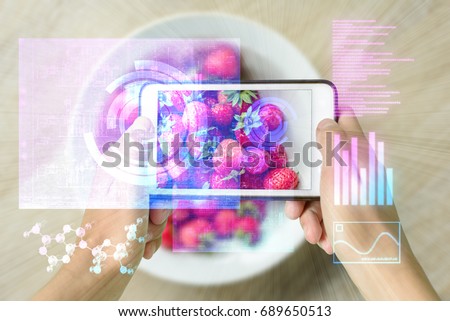 Woman holding a smart device uses reality augmentation to examine a pile of strawberries