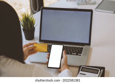 Woman Holding Smart Phone And Credit Card For Shopping Online.Blank Screen Monitor For Graphic Display Montage.Pay For Goods By Credit Card Through A Smartphone .