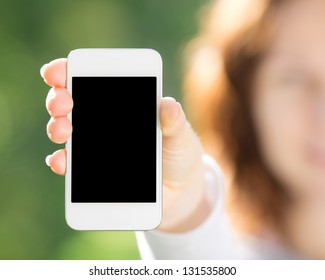 Woman holding smart phone in hand against green spring background. Blank screen with copyspace - Powered by Shutterstock