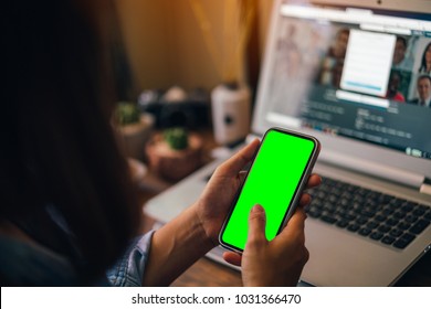 Woman holding a smartphone with green screen isolated on screen background.