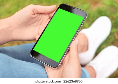 Woman holding smartphone with green screen outdoors, closeup. Gadget display with chroma key. Mockup for design - Powered by Shutterstock