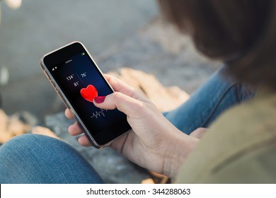 Woman Holding A Smartphone With Health App On Screen. All Screen Graphics Are Made Up.