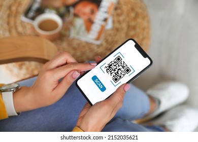 Woman holding smartphone with QR code on screen at home, closeup