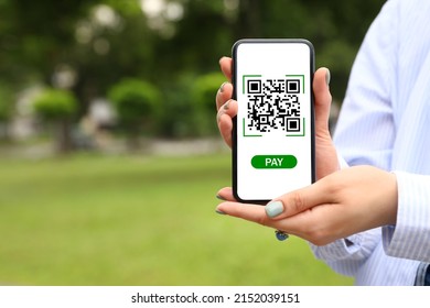 Woman holding smartphone with QR code on screen outdoors, closeup