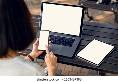 Woman Holding Smartphone And Tablet Screen Blank With Laptop On The Table Mock Up To Promote Your Products.