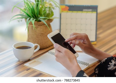 Woman holding smartphone to update calendar with notebook pencil diary vase on table with blurred calendar. planning scheduling agenda and event for 2018. Calendar and Planning concept. - Shutterstock ID 788273845