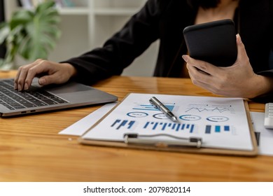 A Woman Holding A Smartphone And Using A Laptop Uses A Smartphone. Chat With Friends Through Instant Messaging To Discuss Business Together And Use Your Laptop To Find Information On The Web.