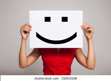 Woman holding a smiling face emoticon - Shutterstock ID 150555248
