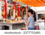 Woman holding smoking incense sticks in chinese temple