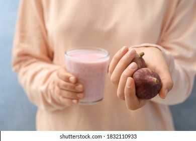 Woman Holding Smoothie And Fresh Figs On Light Blue Background, Closeup