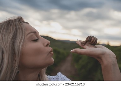 The woman holding snail in vineyard