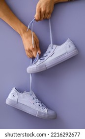 Woman Holding Sneakers On Color Background