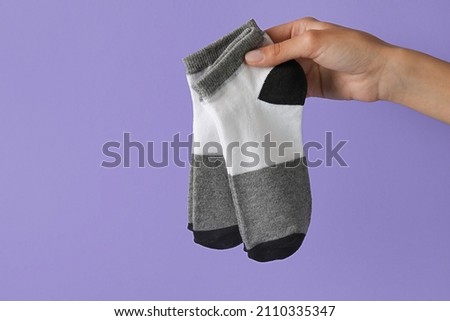 Woman holding socks on lilac background, closeup