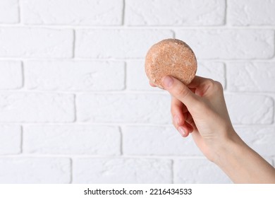 Woman Holding Solid Shampoo Bar Against Brick White Wall, Closeup. Space For Text