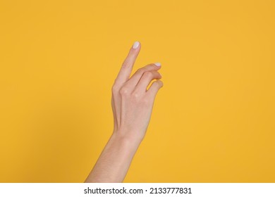 Woman holding something against yellow background, closeup on hand
