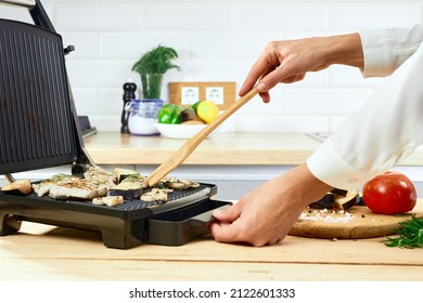 Woman Holding Spatula For Cooking And Serving Barbecue On A Table. Grill Steak On An Electric Stove   At Kitchen. 