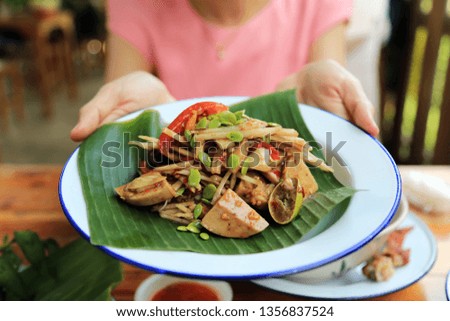 Woman holding spicy thai papaya salad in dish. Thai yummy rustic food.