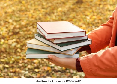 Woman Holding Stack Of Books In Autumn Park, Closeup