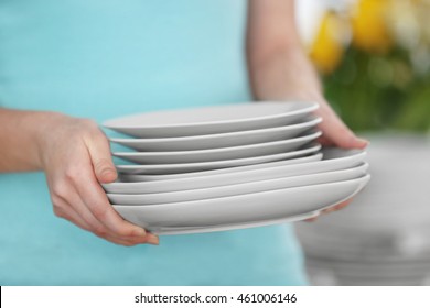 Woman Holding Stack Of Clean Plates, Close Up