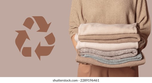Woman holding stack of clothes with used wardrobe for reuse and circular economy logo on beige background. Reusing, recycling materials and reducing waste in fashion, second hand apparel idea - Shutterstock ID 2289196461