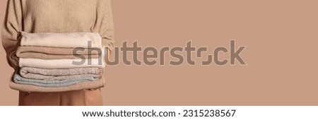 Woman holding stack of clothes with used wardrobe, ready to give away. Circular fashion, fast fashion, clothing recycling, eco friendly sustainable shopping, resale, thrift stores concept. Wide banner