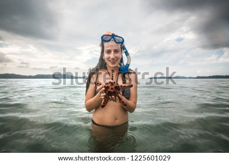 Woman holding starfish in hand showing it in front of the camera, Palawan, Philippines