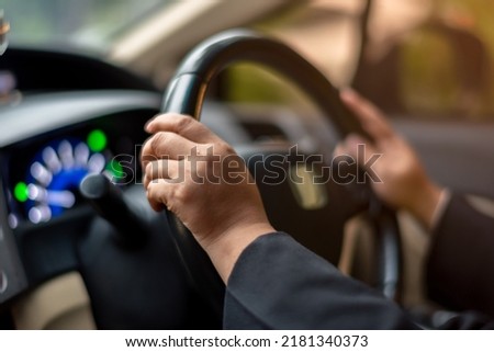 A woman is holding the steering wheel of a car, Safety in driving on the road. He's going to work or somewhere.