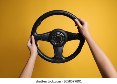 Mujer sosteniendo el volante sobre fondo amarillo, cerrando