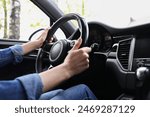 Woman holding steering wheel while driving her car, closeup