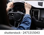 Woman holding steering wheel while driving her car, closeup