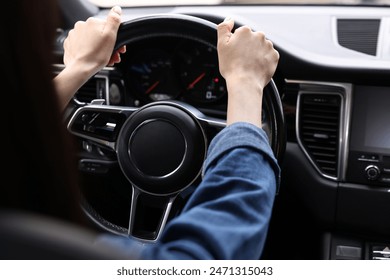 Woman holding steering wheel while driving her car, closeup