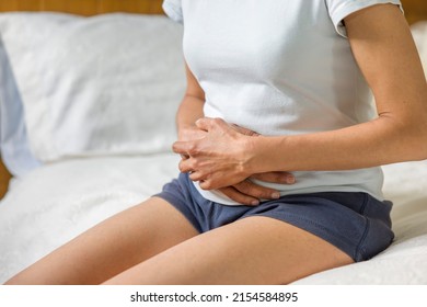 Woman Holding Stomach With Cramp Or Pain. Female Mid Adult Asian Indian, UK