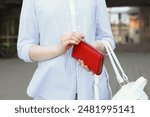 Woman holding stylish red purse outdoors, closeup