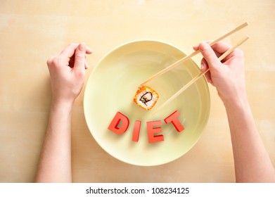 Woman holding sushi with chopsticks top view. Diet sign designed at plate. Diet food concept.