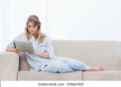 A Woman Holding A Tablet Is Sitting On A Couch