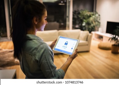 A woman holding a tablet with smart home screen.