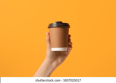 Woman Holding Takeaway Paper Coffee Cup On Orange Background, Closeup