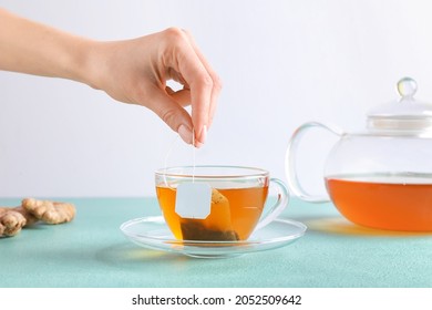 Woman holding teabag on color background