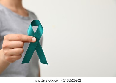 Woman holding teal awareness ribbon against light background, closeup - Shutterstock ID 1458526262