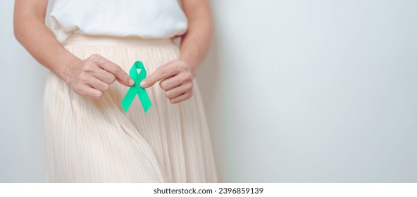 Woman holding Teal Ribbon on abdomen for January Cervical Cancer Awareness month. Uterus and Ovaries, Cervix, Endometriosis, Hysterectomy, Uterine fibroids, Reproductive and World cancer day concept - Powered by Shutterstock