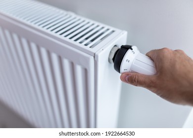 Woman holding temperature knob of heating radiator