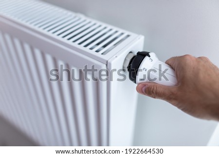 Woman holding temperature knob of heating radiator