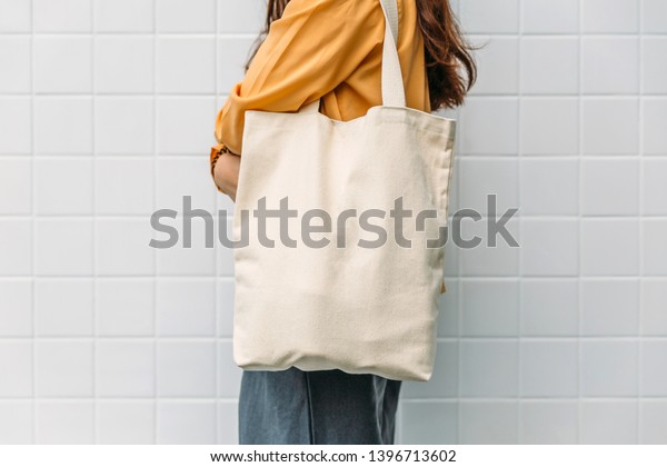 Woman is holding tote bag canvas fabric for\
mockup blank template.