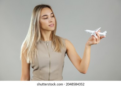 woman holding toy airplane on grey background